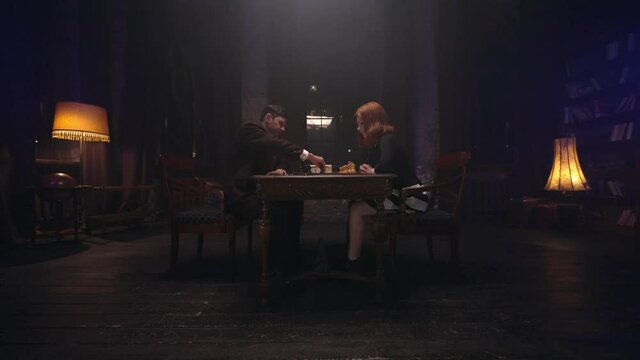 Two chess players man and woman play chess. Debut Accepted Queen's Gambit, King's Gambit, Philidor's Defense. Cinematic filming of a chess game. Antique chess board. This shot can be used for films