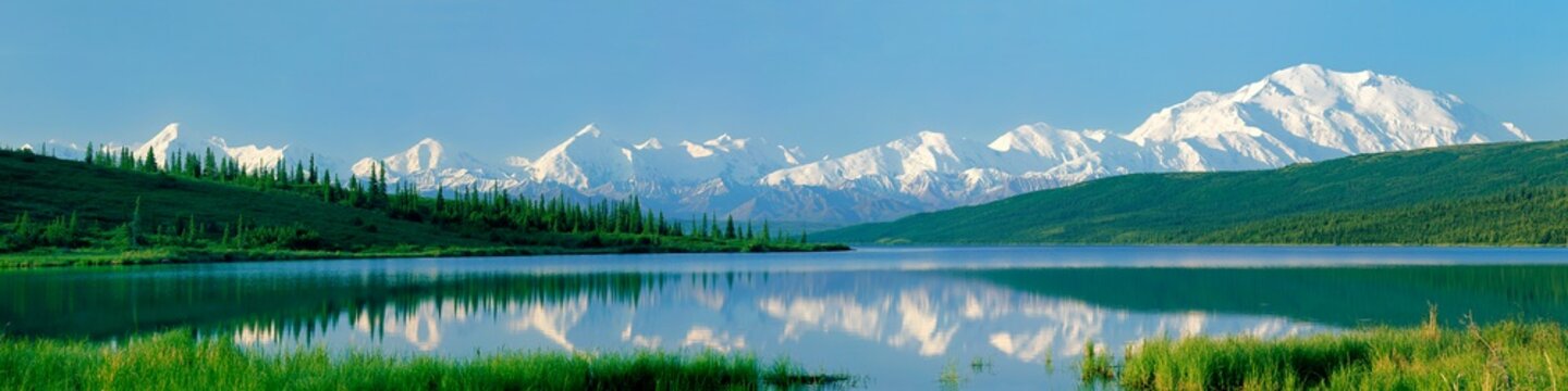 The rugged snow-capped Alaska Range and massive Mount McKinley reflect in Wonder Lake on a rare clear and calm morning in Denali National Park, Alaska