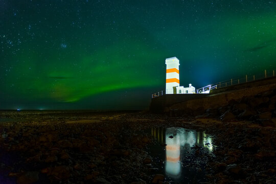 Lighthouse in Iceland with the Northern Lights wrapping around.