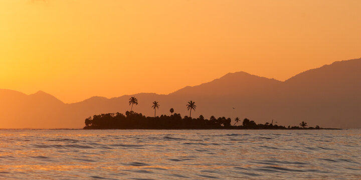 An island sits against the backdrop of Honduras' mountainous coast, Cayos Cochinos, Honduras.