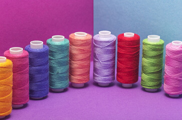  Colored threads on a bobbin on a colored background.
