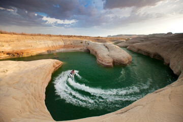 A woman rides a jet ski through a winding red rock canyon in Lake Powell, UT