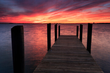 A fiery sunset casts a glow over a fishing pier on South Hutchinson Island, Florida