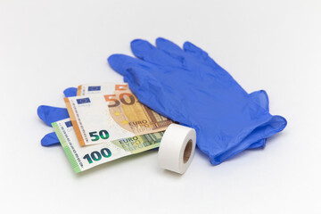 Blue latex gloves, a roll of band-aid and euro bills. Money between the gloves. Adhesive plaster