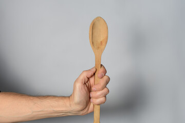 Hand holding wooden spoon on white background
