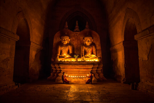 Two young monks offer prayers to Buddha in Bagan, Myanmar.
