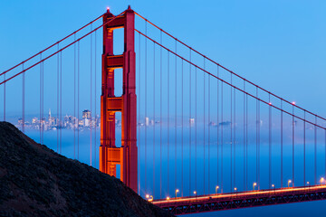 With the San Francisco Bay full of beautiful low lying fog, the commuting traffic glows across the Golden Gate Bridge.