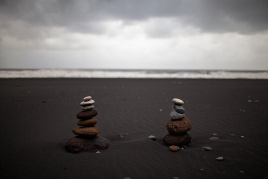 Rock stacks left by tourists to balance on the black sand beaches of Reynishverfi, near Vik, Iceland.
