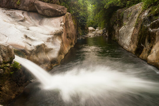 A waterfall spills out into a creek before converging with the Cangrejal River, Honduras.