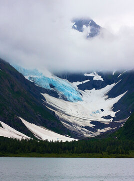 Portage Glacier, Portage, AK: Vertical photo of b blue glacier, with clouds above, snow and pine forest below