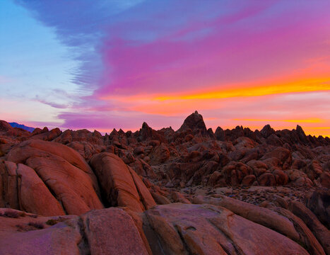 Alabama Hills, Lone Pine, CA: Brilliantly-colored pre-dawn sky casts a rosy glow over foreground boulder field and background low peaks.