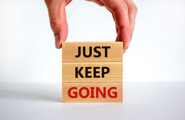 Just keep going symbol. Wooden blocks with words 'Just keep going'. Beautiful white background, businessman hand. Business, just keep going concept, copy space.