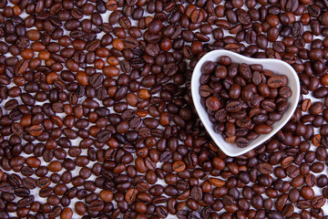 Coffee beans on the table and in a white ceramic heart.