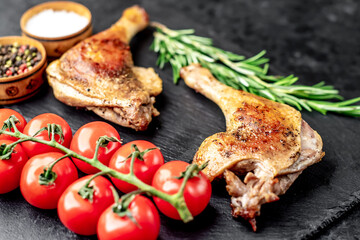 Roasted duck leg with spices on a stone background