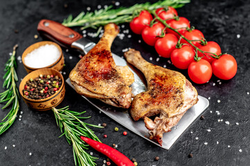 Roasted duck leg with spices on a knife on a stone background