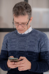 grizzled businessman in a glasses with a phone against the background of glass screen