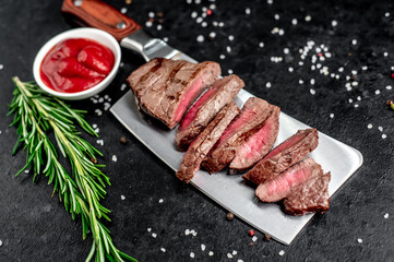 chopped grilled beef steak on a knife on a stone background