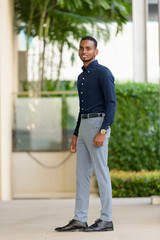 Full length shot of handsome African businessman outdoors at rooftop garden smiling