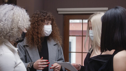Group of women with mask multiracial business team holding a quick standing meeting or talking.
