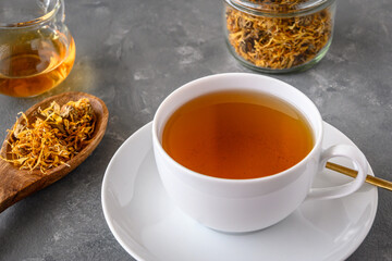 Calendula tea in a white cup. Herbal tea with dried marigold flowers.