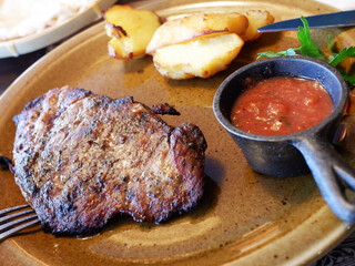meat steak on a plate with potatoes and sauce. dinner at a restaurant.