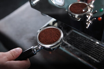 Coffee filter holder or coffee horn. Coffee machine is out of focus. Ground fresh coffee. Photos without people. Top view.