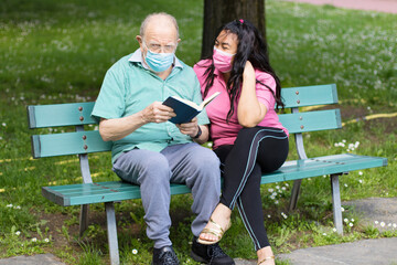 elderly patient is holding and reading a book with his caregiver while spending time together