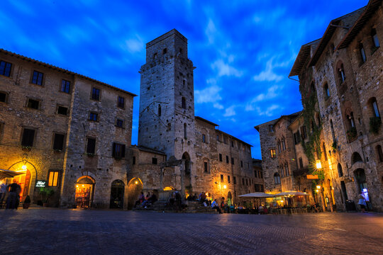 Piazza della Cisterna illuminated at night in the Medieval walled city of San Gimignano, Tuscany, Italy