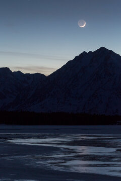 Waxing crescent moon setting over Teton Mountains and Jackson Lake, Grand Teton National Park, Wyoming