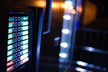Illuminated vending machine panel with blurred background.
