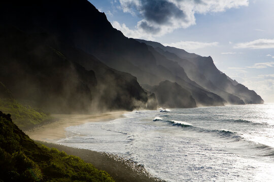 The fluted ridges of the Na Pali Coast rise above the crashing surf on the north shore of Kauai, Hawaii.