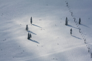 Crowds of skiers and snowboarders ride lifts and descend the groomed runs at the Summit at Snoqualmie ski resort on Snoqualmie Pass, Washington.
