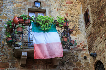 Patriotic display of the Italian flag from a balcony in the medieval walled city of Pienza, Tuscany