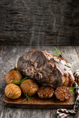 Roast lamb leg with potatoes and rosemary on cutting board