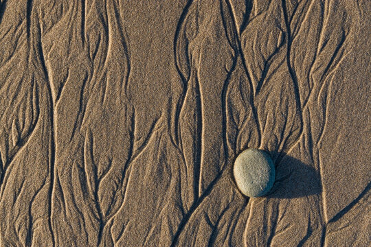 Flowing water creates intricate patterns in the sand on a southern California beach.