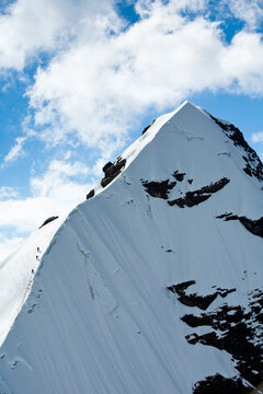 Climbers descend the steep pyramid from the glacier-covered summit of Mt. Pequeno Alpamayo in Bolivia's Cordillera Real.