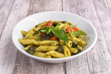Penne pasta with pesto of tomatoes, black olives and basil
