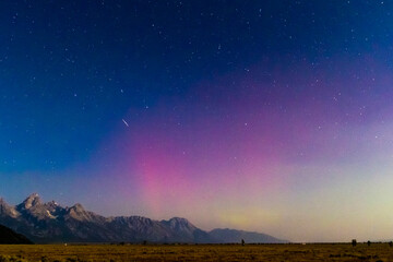 A meteor streaks across the night sky into the northern lights above Antelope Flats in Grand Teton National Park, Wyoming.