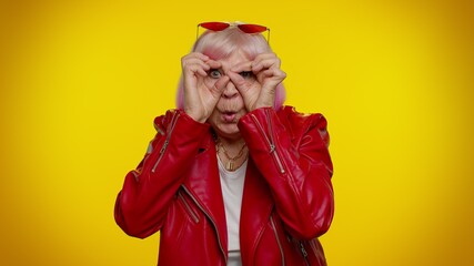 Nosy curious senior granny woman closing eyes with hand, spying through fingers, hiding and...