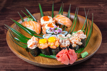Sushi and rolls with raw quail eggs on wooden plate with green leaves