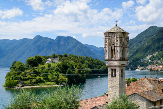 Como, Italy July 17 2019: Ancient medieval Church tower with island and mountain in background