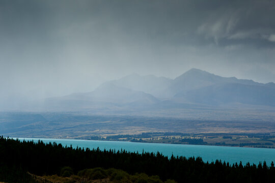 A rainstorm clears from Aoraki / Mt. Cook National Park revealing the aqua-colored glacial melt of Lake Pukaki and the peaks of the Southern Alps in New Zealand's South Island.