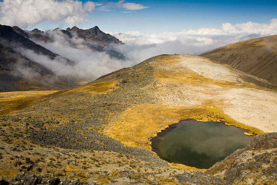 The glacier-covered summit of Mt. Akhamani (18,589'/5,666m) rises above the puna and an alpine lake in the Apolobamba Range in Bolivia.