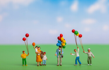Obraz na płótnie Canvas Miniature people : Happy family holding balloon on green background