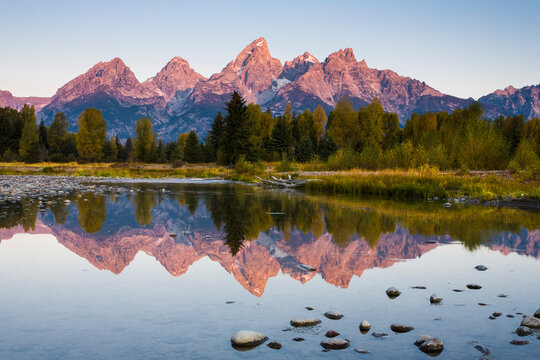 The first light of the day hits the Teton Mountains viewed from Schwabacher Landing in Grand Teton National Park, Wyoming.