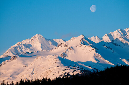 Early light on the mountains outside of Haines, Alaska with the moon still out.