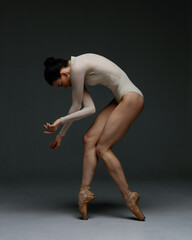 Obraz na płótnie Canvas Young beautiful skinny ballerina is posing in studio