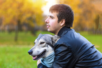 young happy man hugging dog. pet adoption.  czechoslovak with male owner. boy walking, playing, training Saarlos wolfdog in the park outdoors. soft focus