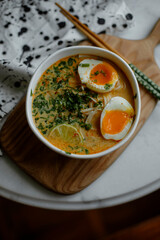 ramen soup on a white table top view. Asian ramen soup with split egg lime and herbs. a bowl of Japanese noodle soup with chopsticks.	
