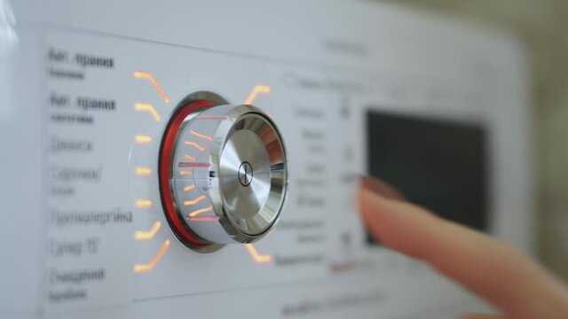 Woman's hand turning on and off the switch of the washing machine